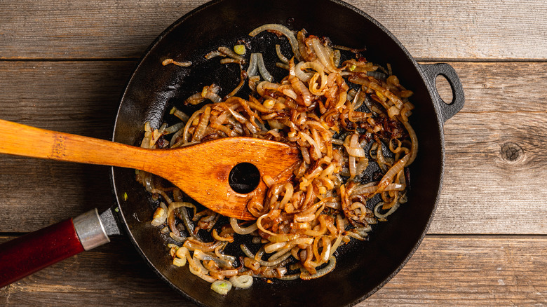 Caramelized onions in skillet with wooden spatula