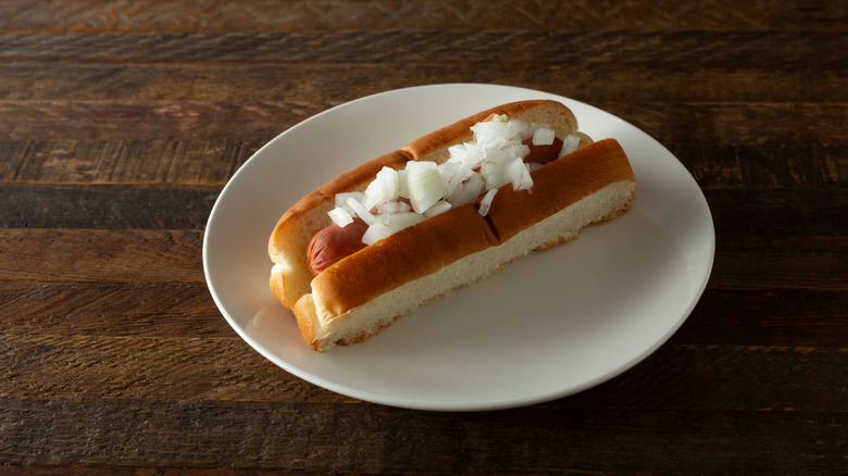 Hot dog on plate topped with diced onion