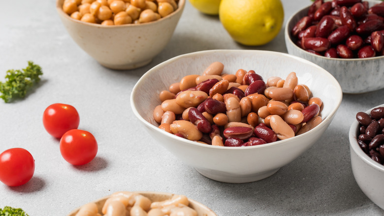 Several small white bowls of different types of canned beans
