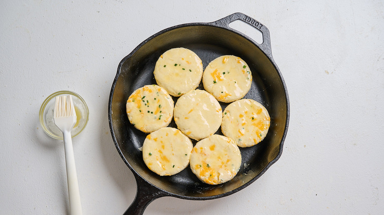 brushing biscuits with butter in a cast iron pan