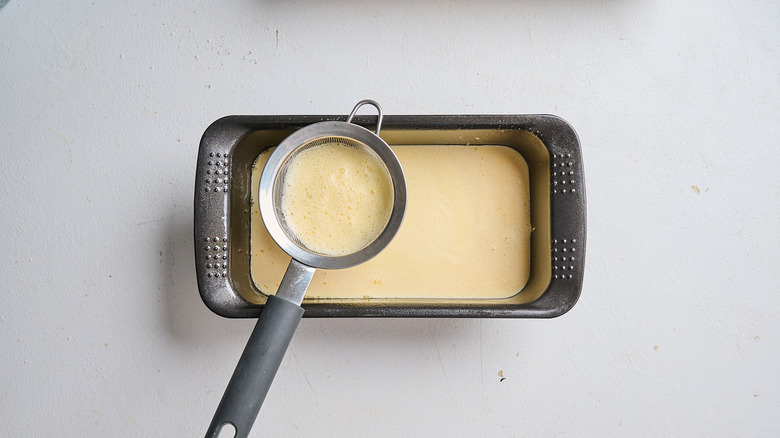 Straining egg mixture into a pan
