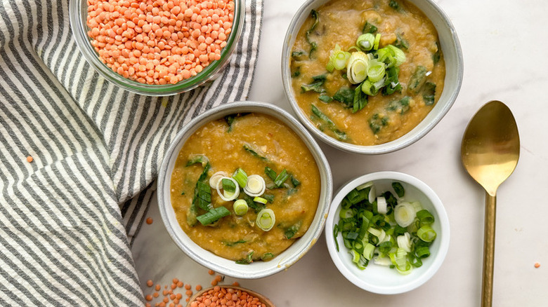 Two bowls of miso red lentil soup, garnished with green onions