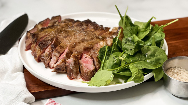 Sliced steak on plate with leafy green salad