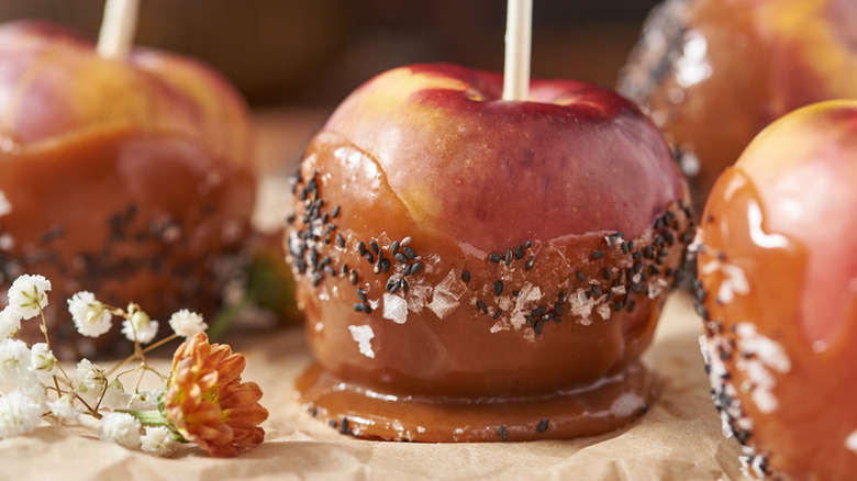 Caramel apple on stick garnished with black sesame seeds and flaky salt