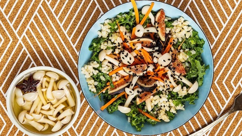 Plate of salad with brown rice, pickled mushrooms, kale, and fig slices