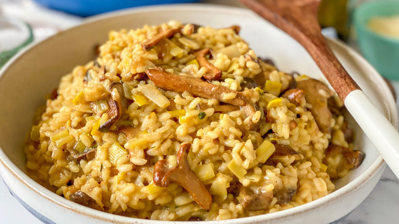 Bowl of mushroom risotto with wooden spoon resting on top