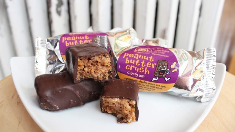 Two Zingerman's Peanut Butter Crush candy bars on a plate next to their wrappers