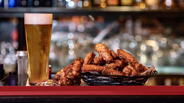 Plate of wings and glass of beer on bar