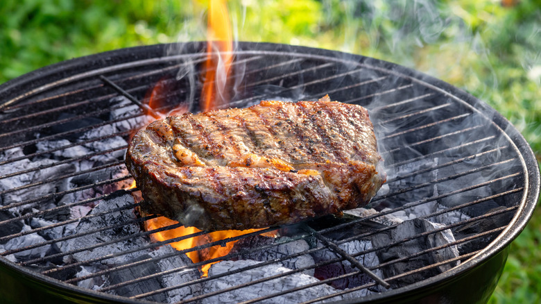 Steak being grilled with a little flame