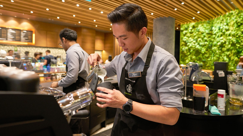 Starbucks worker pouring steamed milk