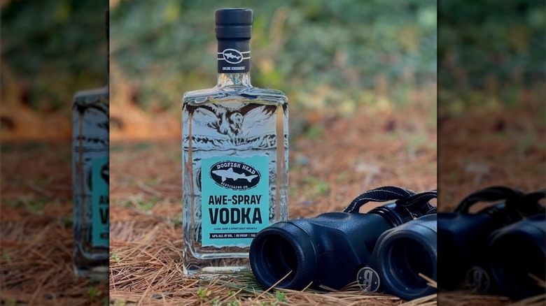 Label view of Dogfish Head Awe-Spray Vodka outside alongside binoculars on the ground