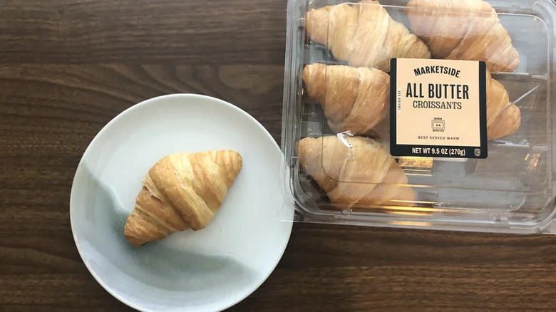 A Marketside All Butter Croissant on a plate next to a 6-pack of the croissants