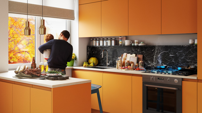 Parent and child in a bright orange kitchen with a dark marble backsplash