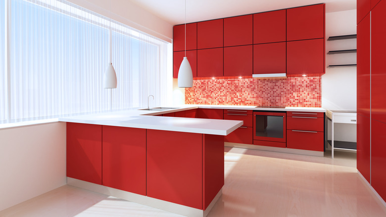 Bright kitchen with cherry red cabinets and white counters, a large window on the left