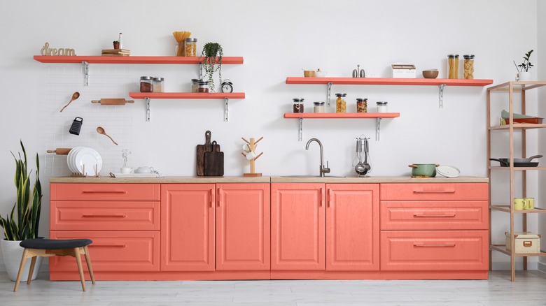 Kitchen with coral pink lower cabinets, wooden countertop, and coral open shelves