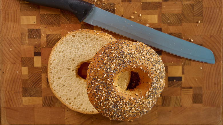 A sliced bagel and a knife on a cutting board