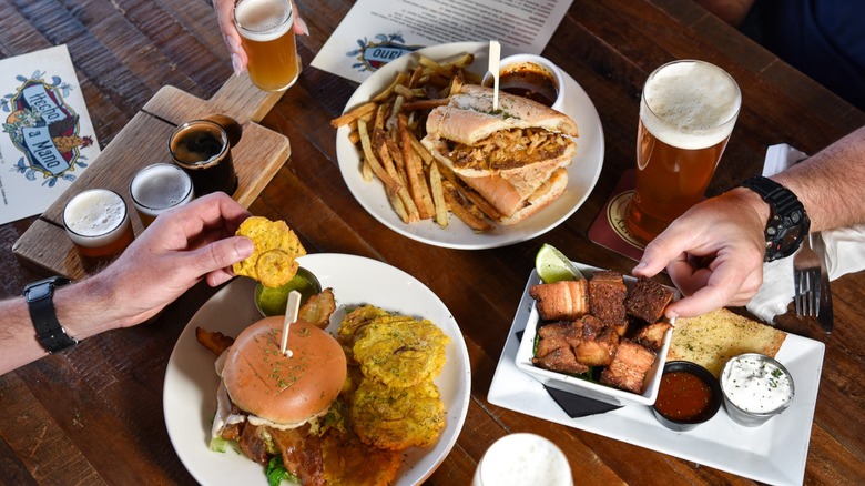 Table with pork belly, sandwiches, burgers, and beer flights