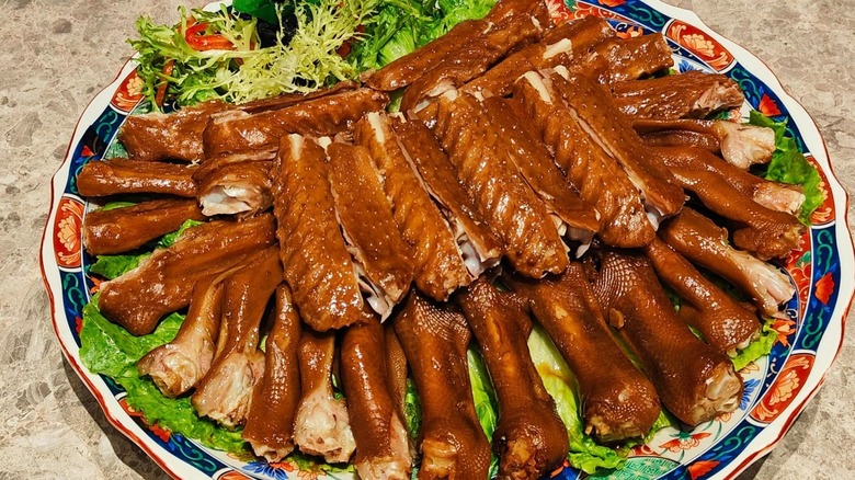 Pieces of marinated goose on a decorative plate with greens