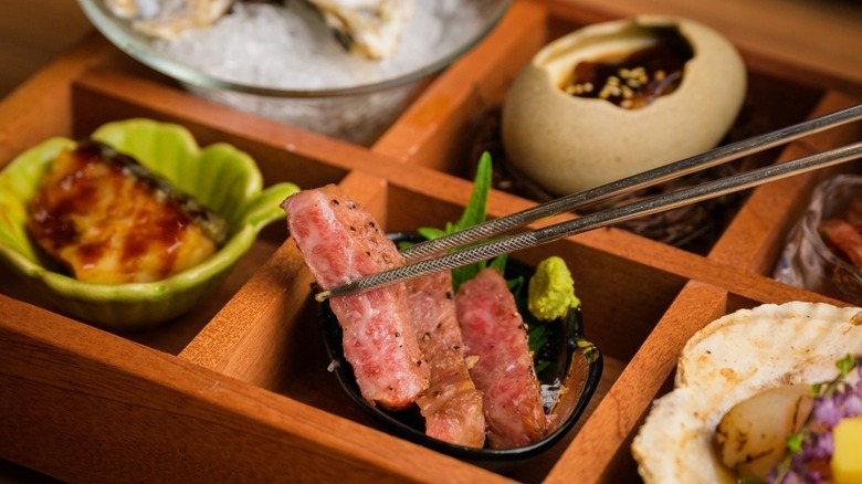 Slice of Wagyu beef in front of a box with assorted small bites