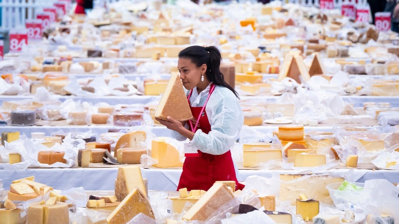Woman smelling a block of cheese and surrounded by cheeses at the World Cheese Awards