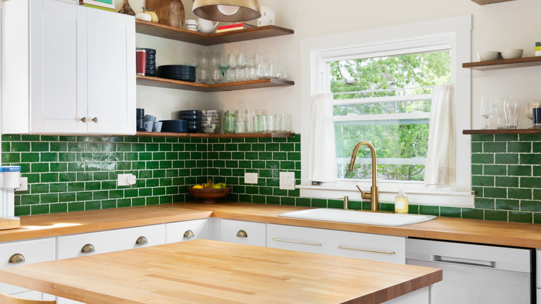 Kitchen with green subway tile backsplash and light butcher's block countertops