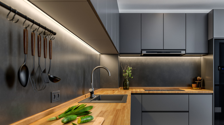 Modern kitchen with black cabinets and countertops, and a light butcher's block countertop