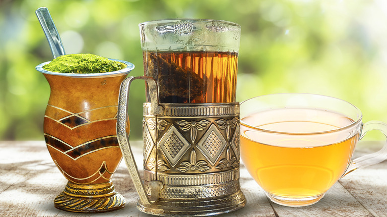 Three different types of tea on wooden surface with tree behind