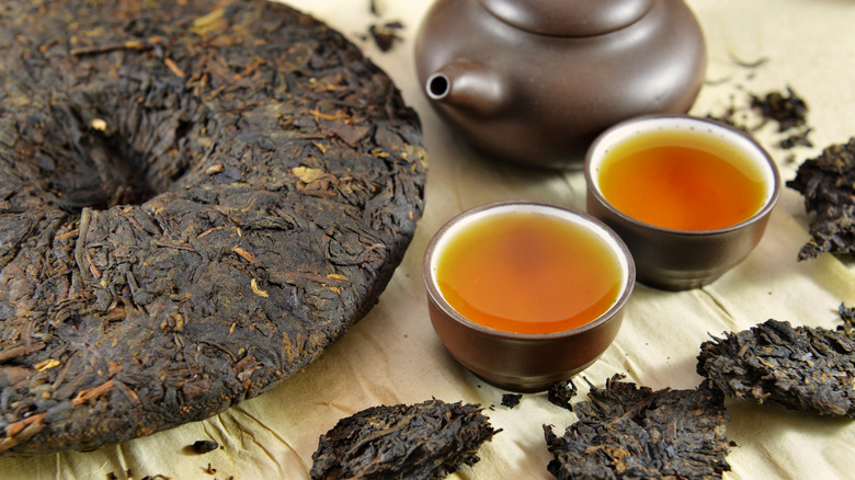 Large brick of pu-erh tea with two brewed cups of tea
