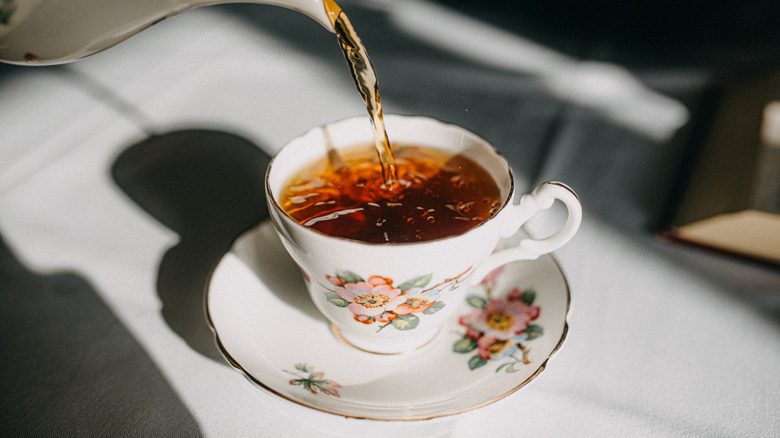 Black tea being poured into china cup