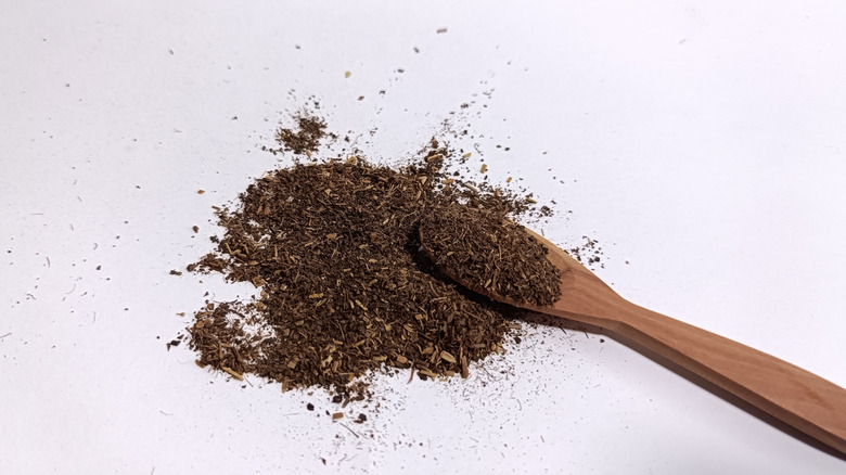 Finely ground black tea spilling out of wooden spoon