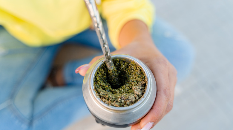 Hand holding Yerba mate being prepared in tea mug