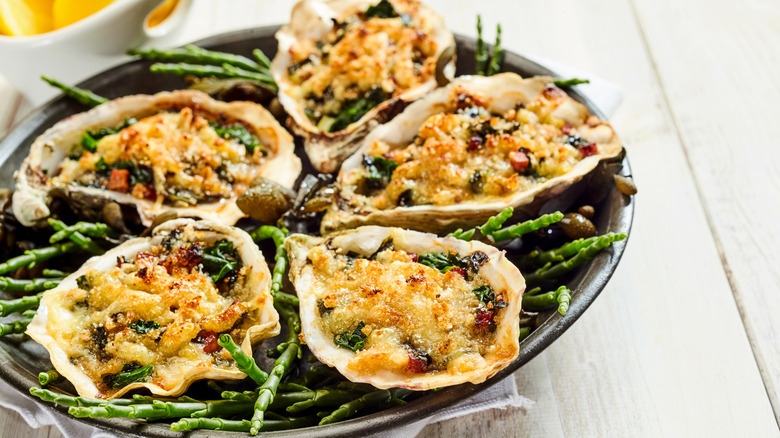 Plate of oysters with broiled breadcrumb topping on top of green stems