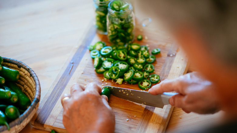 Woman chopping jalapeños on cutting board