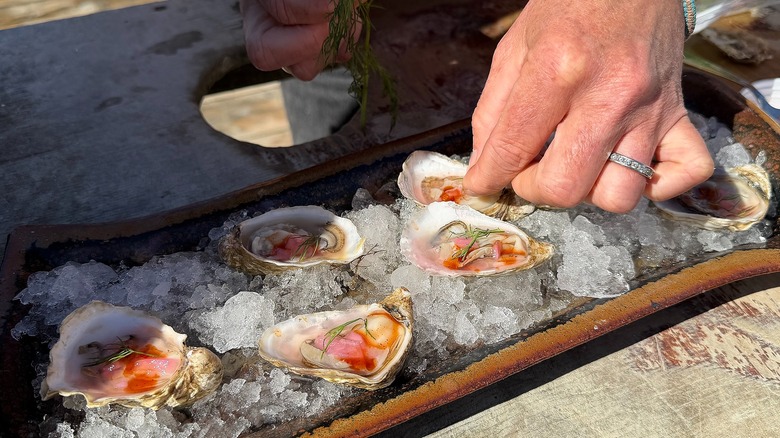 Oysters on ice in tray with mignonette, lemon juice, dill