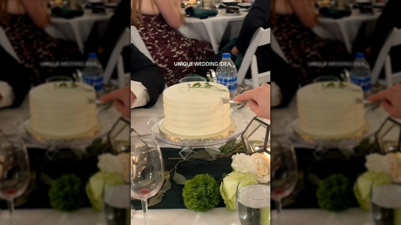 Person slicing into a single-tiered white cake at a wedding table