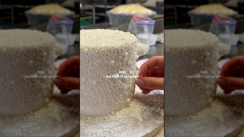 Hand covering cake in white edible pearls