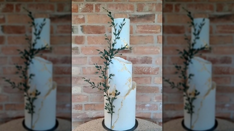White and gold floating tier wedding cake with faux foliage