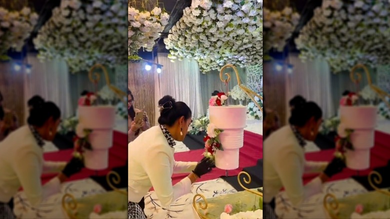 Person decorating a hanging wedding cake with flowers