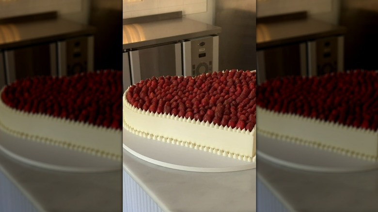 Flat, heart-shaped wedding cake topped with raspberries