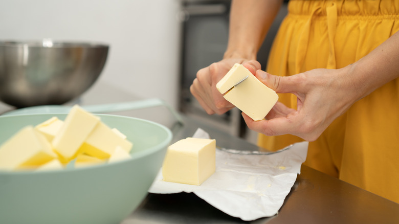 Person cutting butter in a kitchen