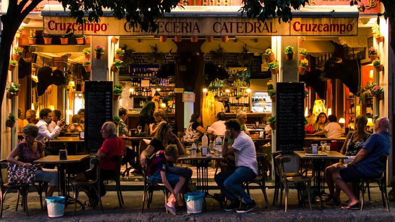 Diners are pictured eating outside a restaurant in Seville at night.