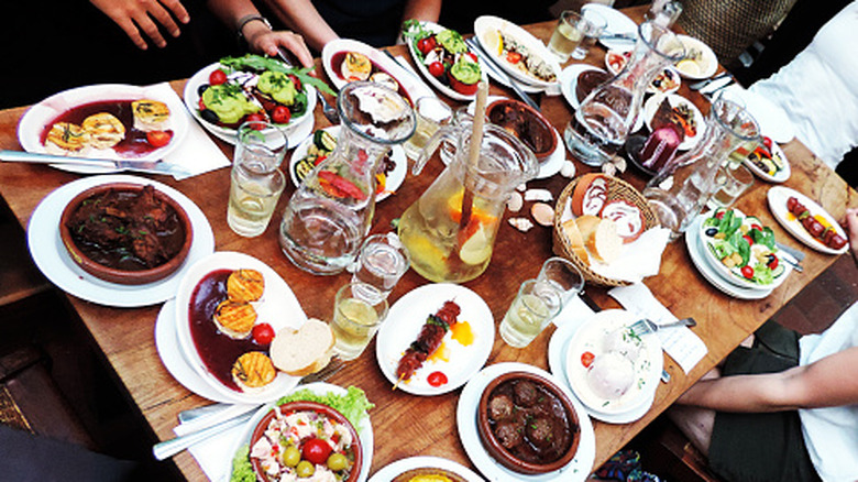 A large table is pictured with many food dishes before a group begins to eat lunch.