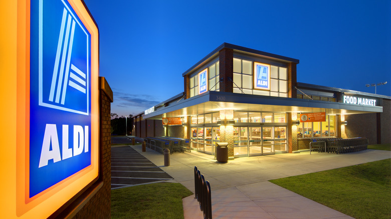 Well-lit Aldi sign and Aldi food market outside at night.