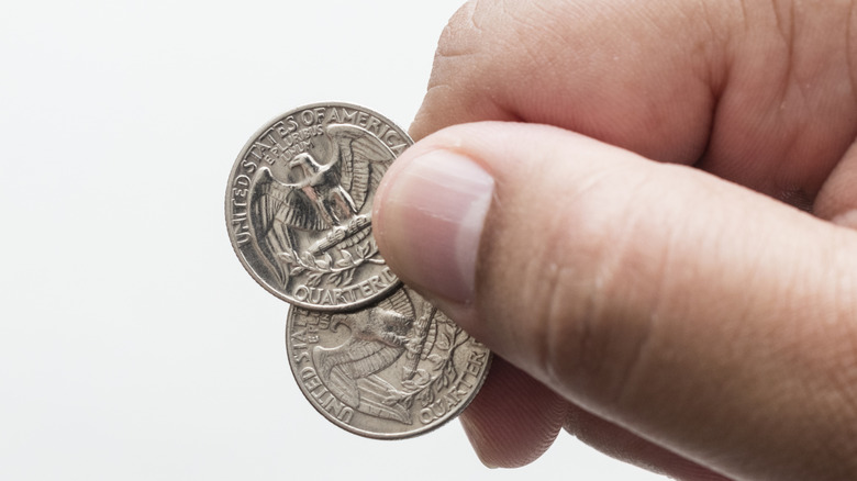 Hand holding two quarters.