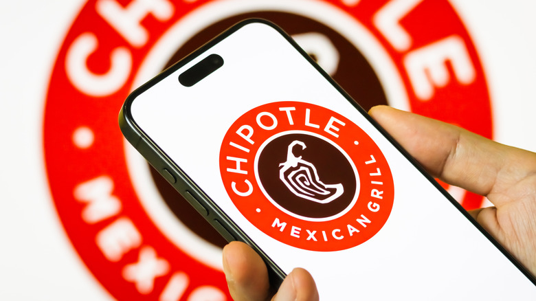 Hand holding black phone with Chipotle logo