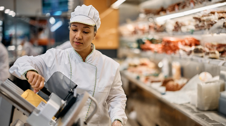 Deli worker slicing meat at store