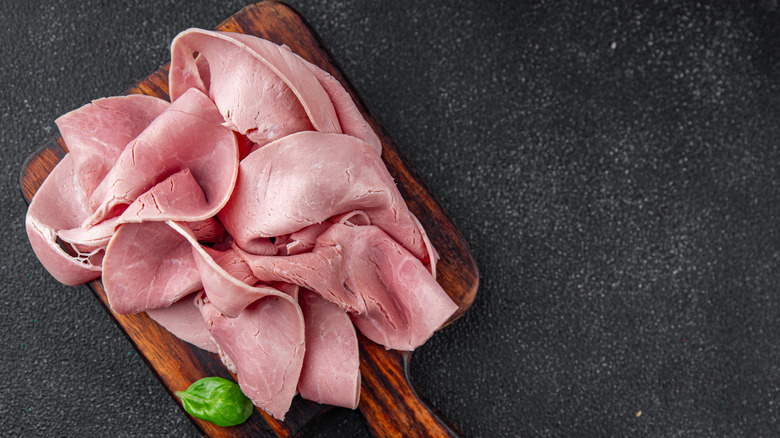 Sliced deli meat on wooden cutting board