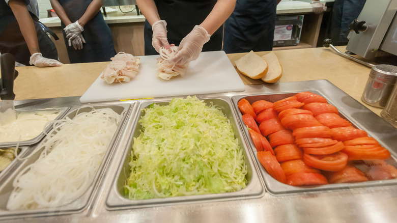 Sandwich ingredient stations behind the barrier at Jersey Mike's