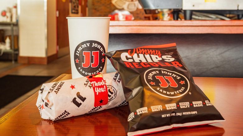 Jimmy John's meal without a bag on a table with a sandwich and cup and chips