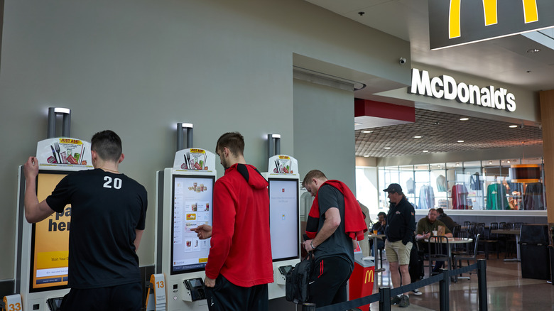 People ordering food on the self-service kiosks at a McDonald's
